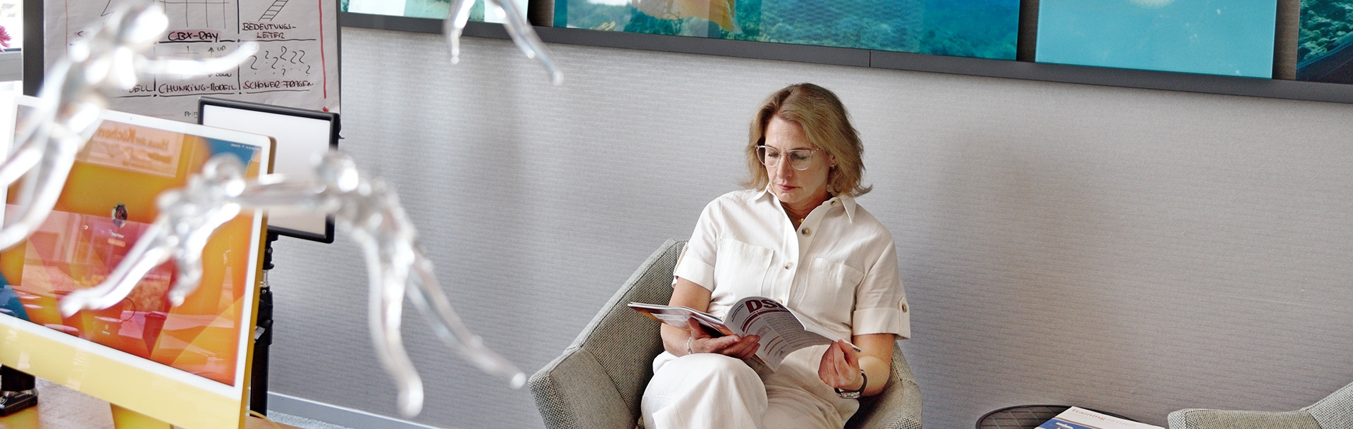 Frau Palzer sitzt in einem Sessel und blättert in einer Zeitschrift